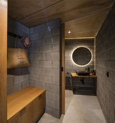 a bathroom with a wooden counter top next to a brick wall and a round mirror on the wall