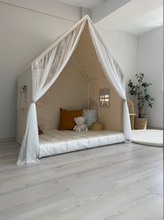 a bed with a white canopy and pillows on it's side in a room