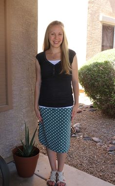 a woman standing in front of a house next to a potted plant and smiling