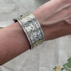 a close up of a person's arm wearing a silver bracelet