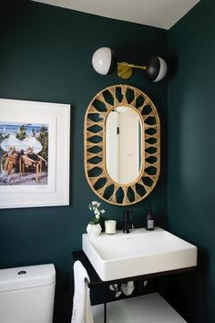 a white sink sitting under a mirror next to a wall mounted toilet and vanity in a bathroom