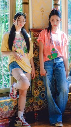 two girls standing next to each other in front of a window