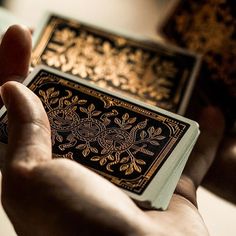 a person holding up a playing card in their left hand, with both hands on it