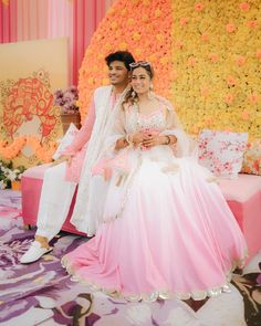 a man and woman sitting next to each other in front of a flower covered wall