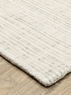 a white rug on top of a wooden floor next to a wood flooring board