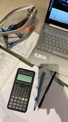 an open laptop computer sitting on top of a desk next to a calculator