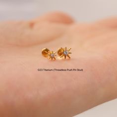 a pair of tiny diamond stud earrings on someone's hand with the caption, q23 tantum thunderess flush pin studs