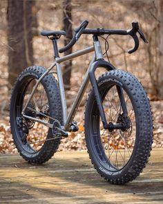 a bike is parked on the ground in front of some trees with leaves around it