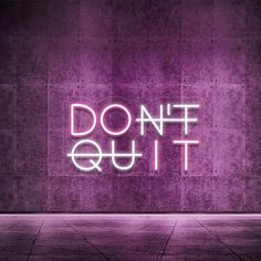 a neon sign that says don't quit in front of a purple wall with the words don't quit on it