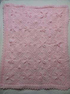 a pink crocheted blanket sitting on top of a table