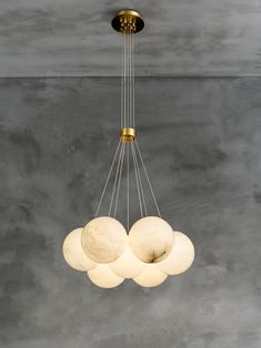 a chandelier with five white balls hanging from it's center and four gold rings on each end