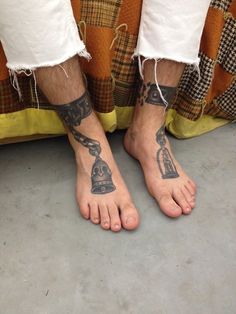 a person with tattoos on their feet standing next to a bed