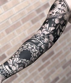 an arm with black and white flowers on it, next to a brick wall that says jayeewallingford