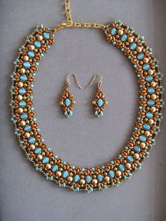 a necklace and earring set with turquoise beads on a gray background, in gold tone