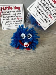 a blue stuffed animal sitting on top of a wooden table next to a sign that says little hug