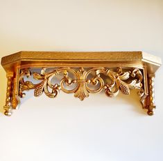 an ornate gold shelf on a white wall