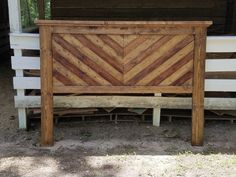 a bed frame made out of wooden planks in front of a building with white siding