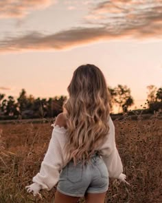 a woman standing in a field with her back to the camera