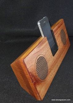 a wooden phone holder with an iphone on it's side and a speaker attached to it