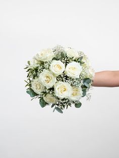 a bouquet of white roses is held by someone's hand on a white background