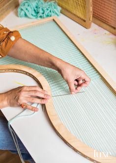 a woman is working on an art project with wood and yarn in front of her