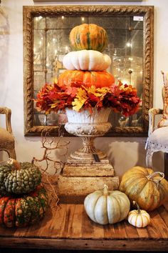 an arrangement of pumpkins and gourds on a table in front of a mirror