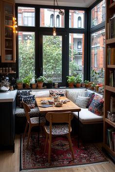 a kitchen table with two chairs and a bench in front of a window filled with plants