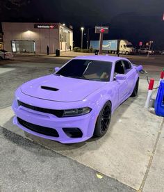 a purple dodge charger parked in front of a gas station