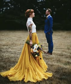 a woman in a yellow dress and a man in a blue suit stand next to each other