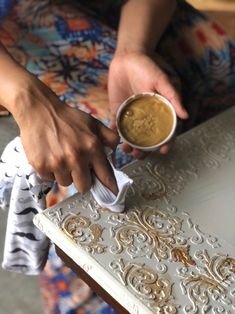 a person is holding a napkin and dipping something into a cup on top of a table