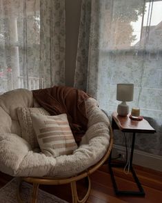 a chair that is sitting in front of a window with pillows on top of it