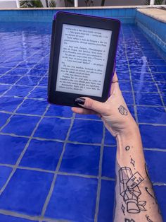 a person holding up an electronic device in front of a swimming pool with blue tiles