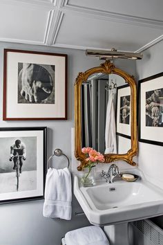 a bathroom sink sitting under a mirror next to pictures