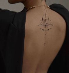 the back of a woman's neck with a flower tattoo on it