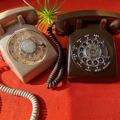 an old - fashioned telephone sits on a red tablecloth with a plant in the background