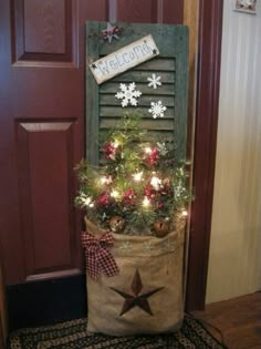 a christmas tree in a sack with lights on it and a welcome sign hanging from the front door