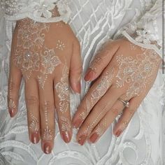 a woman's hands with white lace on them and her wedding ring in the other hand