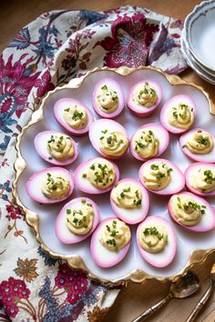 small deviled eggs are arranged on a platter next to a plate with silverware