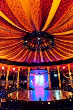 an empty stage is lit up with colorful lights and draping for the ceiling