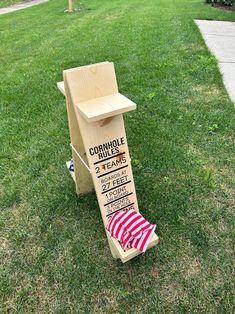 a wooden sign sitting on top of a green grass covered field next to a sidewalk