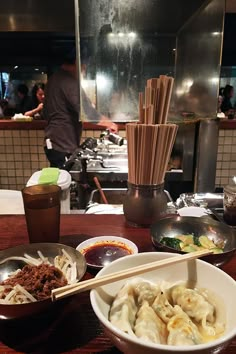 a table topped with bowls filled with food and chopsticks on top of it