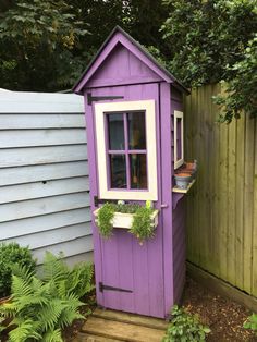 a purple outhouse sitting next to a wooden fence