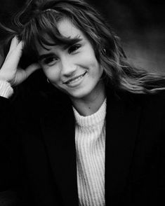 a black and white photo of a woman with her hair in the wind, smiling