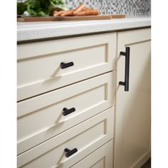 an image of a kitchen setting with white cabinets and black handles on the drawer pulls