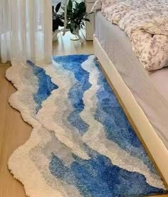 a blue and white rug on the floor next to a bed