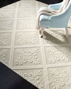 a blue chair sitting on top of a rug next to a white chair and wooden floor