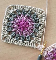 two crocheted grannys are sitting on a table next to a knitting needle