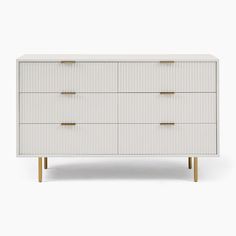 a white dresser with four drawers and two gold pulls on the top, against a white background