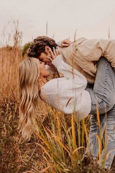 a man and woman kissing in tall grass