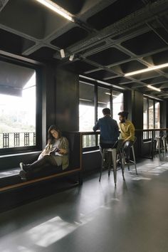 two people sitting on chairs in a room with large windows and floor to ceiling windows